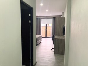 A modern apartment with a hallway leading to a bedroom with a large window and a balcony.