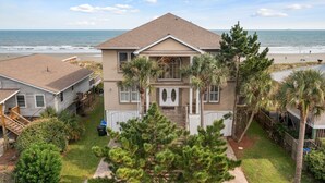 A two-story house with a front porch, a small garden, and a view of the beach. - All Occasion House! Grand Oceanfront Home, Direct Beach Access, Large Ocean View Windows (Folly Beach)