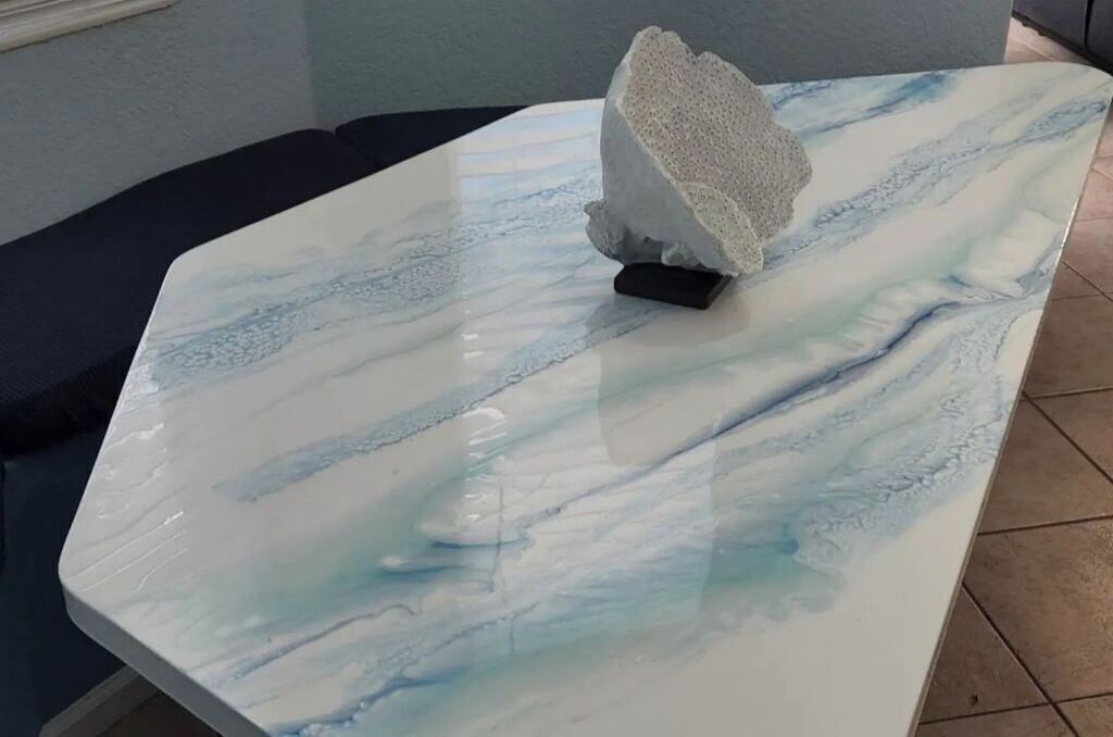 A marble table with a white and blue pattern, a small sculpture on a black base, and a dark-colored sofa in the background.