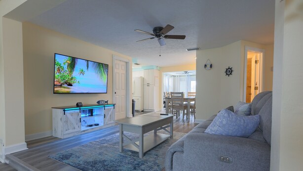 A living room with a gray sofa, a coffee table, a flat-screen TV, and a ceiling fan. - Endless Summer Pool Vibes (Largo)