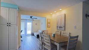 A dining area with a wooden table and chairs, a ceiling fan, and a view of a balcony. - Endless Summer Pool Vibes (Largo)