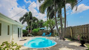 A backyard with a swimming pool, blue chairs, and a wooden fence. - Endless Summer Pool Vibes (Largo)
