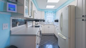 A kitchen with white cabinets, a black tiled floor, a built-in oven, and a refrigerator. - Endless Summer Pool Vibes (Largo)