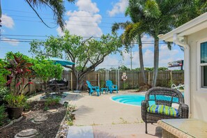 A backyard with a swimming pool, outdoor furniture, and a wooden deck.