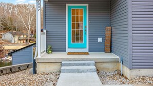 Una casa con una puerta turquesa, un buzón y un pequeño jardín.