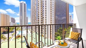 Ein Balkon mit Blick auf hohe Gebäude, einen Tennisplatz und einen Pool.