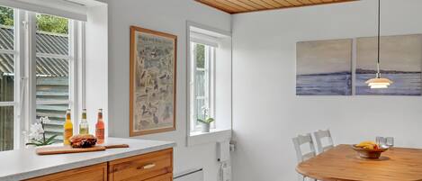 A kitchen with wooden cabinets, a dining table, and artwork on the walls.