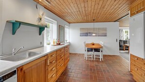 A kitchen with wooden cabinets, a sink, and a dining area with a table and chairs.