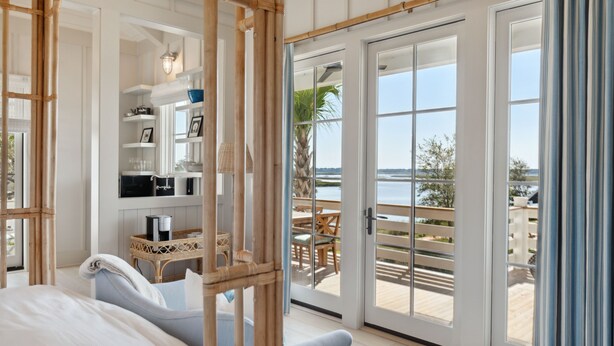 Un dormitorio con un amplio ventanal corredera que da a un balcón con vistas a la playa.