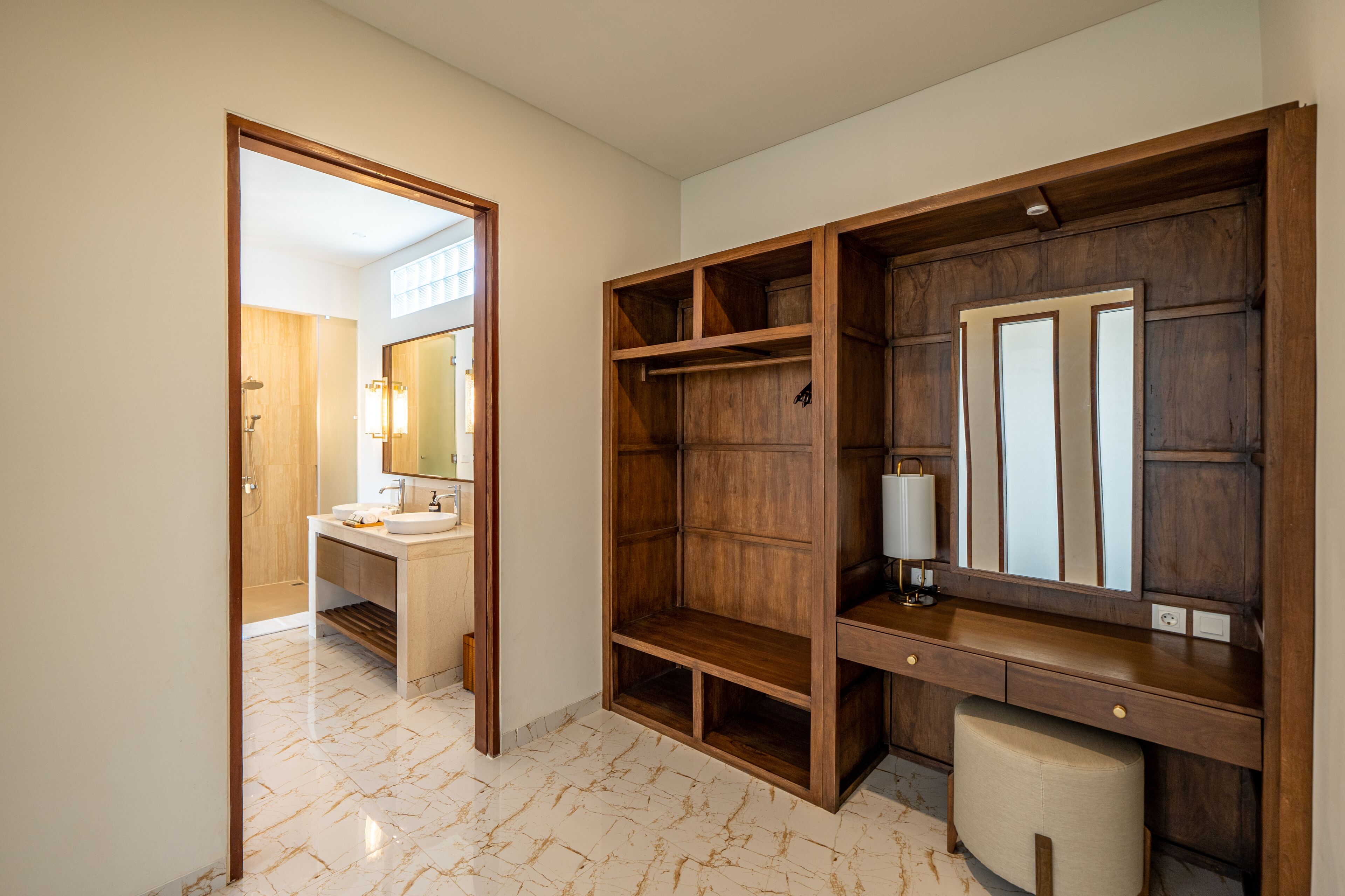 Un baño moderno con tocador de madera, un espejo grande y suelo de mármol.