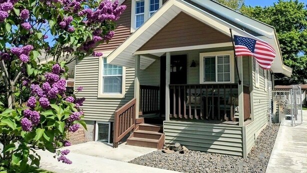 Een huis met twee verdiepingen, een voortuin en een klein terras, met een Amerikaanse vlag.
