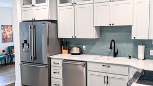 Een moderne keuken met witte kasten, roestvrijstalen apparatuur en een blauwe achterwand.