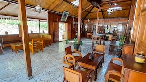 A wooden interior with stone flooring, wooden furniture, and potted plants. - Edge Resort Yogyakarta (Giricahyo)