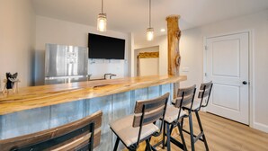 Cocina con barra de madera, electrodomésticos de acero inoxidable y taburetes de bar.