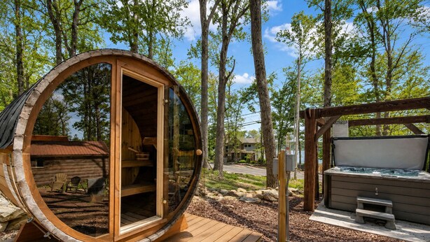 Una cabaña de madera con un ventanal circular, un jacuzzi y una terraza.