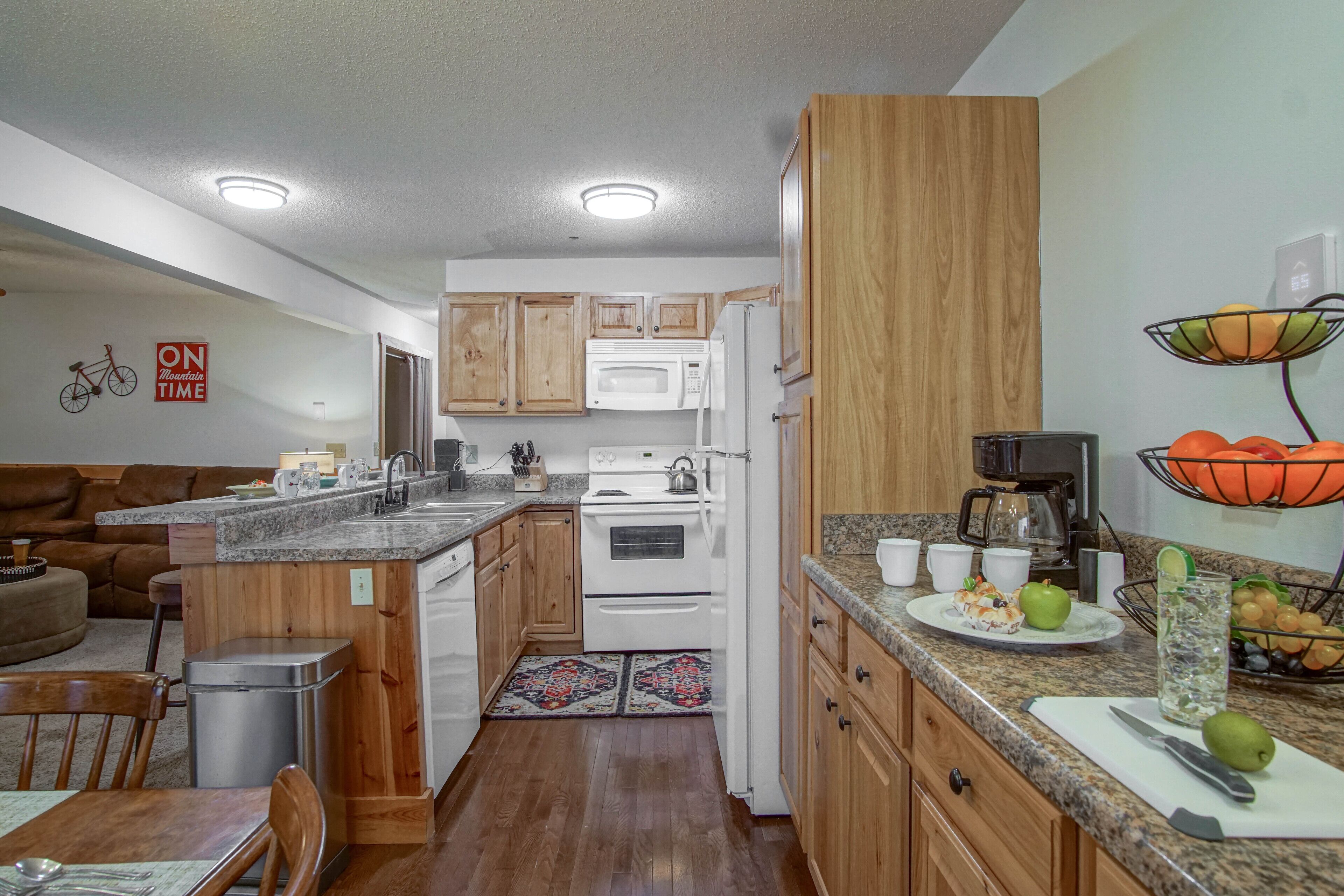 A compact kitchen with wooden cabinets, a microwave, a stove, and a coffee maker.