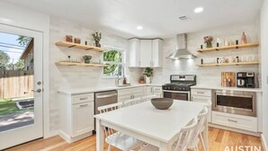 A modern kitchen with white cabinetry, a central island, and built-in appliances.