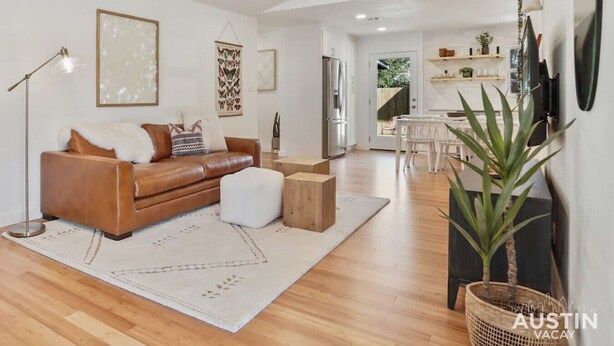 A spacious living room with a leather sofa, a coffee table, and a large plant.