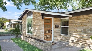 A modern house with a stone facade, large windows, and a well-maintained lawn.