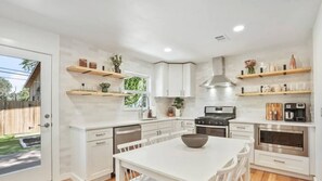 Une cuisine moderne avec des meubles blancs, un îlot central et des appareils électroménagers intégrés.