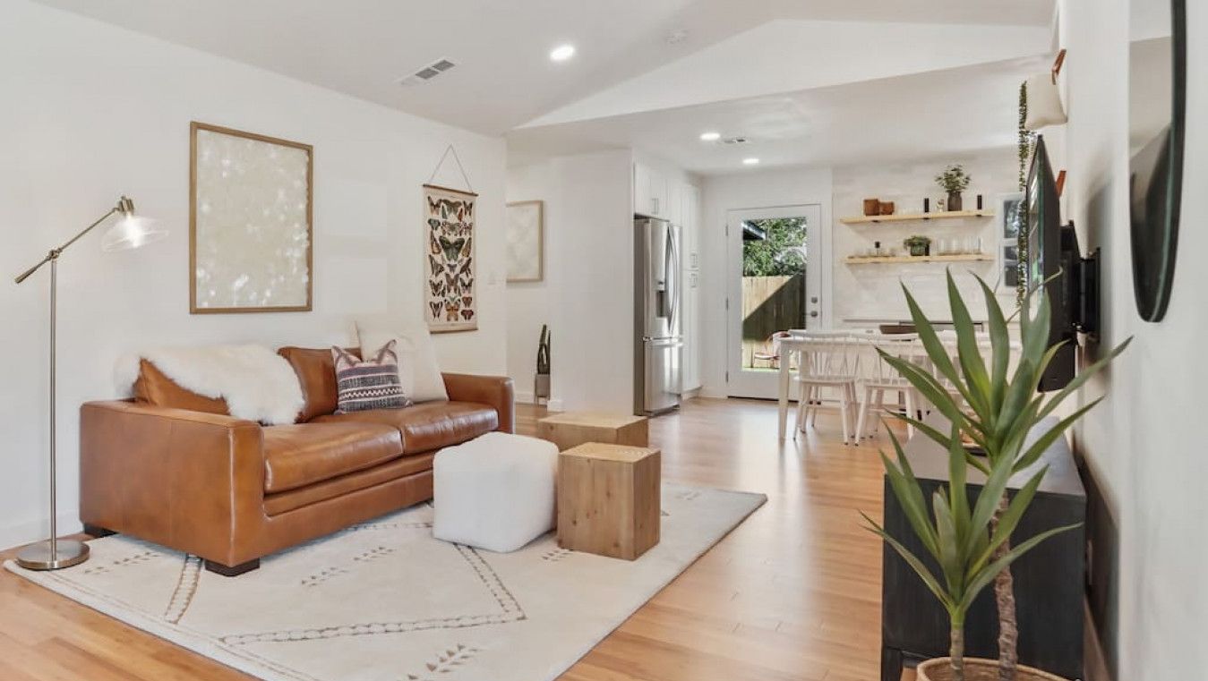 A spacious living room with a leather sofa, a coffee table, and a large plant.