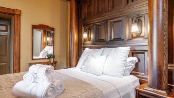 A hotel room with a large bed, wooden headboard, a mirror, and a nightstand with a lamp.