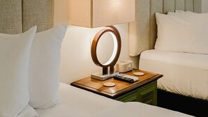A hotel room with a bed, a bedside table with a lamp, a remote control, and a small decorative item. - Wild Iris Room at The Wildflower Inn (Gold Beach)