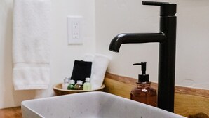 A bathroom with a rectangular sink, a black faucet, a towel ring, and a soap dispenser on the countertop. - Wild Iris Room at The Wildflower Inn (Gold Beach)