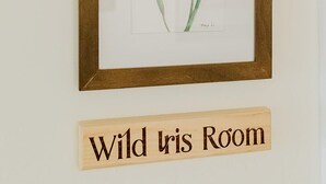 A framed botanical illustration of a wild iris with a wooden sign below it reading "Wild Iris Room". - Wild Iris Room at The Wildflower Inn (Gold Beach)