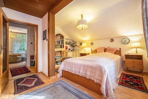 A bedroom with a large bed, bedside tables, a bookshelf, and a window. - 'Romantic Holiday Home' with Garden & Wi-Fi (Gerdau)