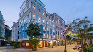 A multi-story hotel with a classic architectural design, featuring a prominent glass balcony on the upper floor. - Ha Long Essence Classic Hotel (Bai Chay)