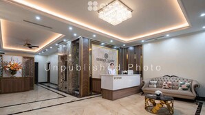 A hotel reception area with a marble floor, a reception desk, a chandelier, and a sofa with decorative pillows. - Ha Long Essence Classic Hotel (Bai Chay)