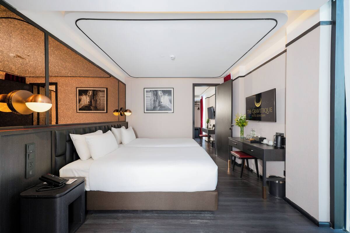 A modern hotel room with a large bed, a desk, and a mirror.