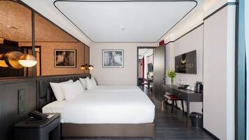 A modern hotel room with a large bed, a desk, and a mirror.