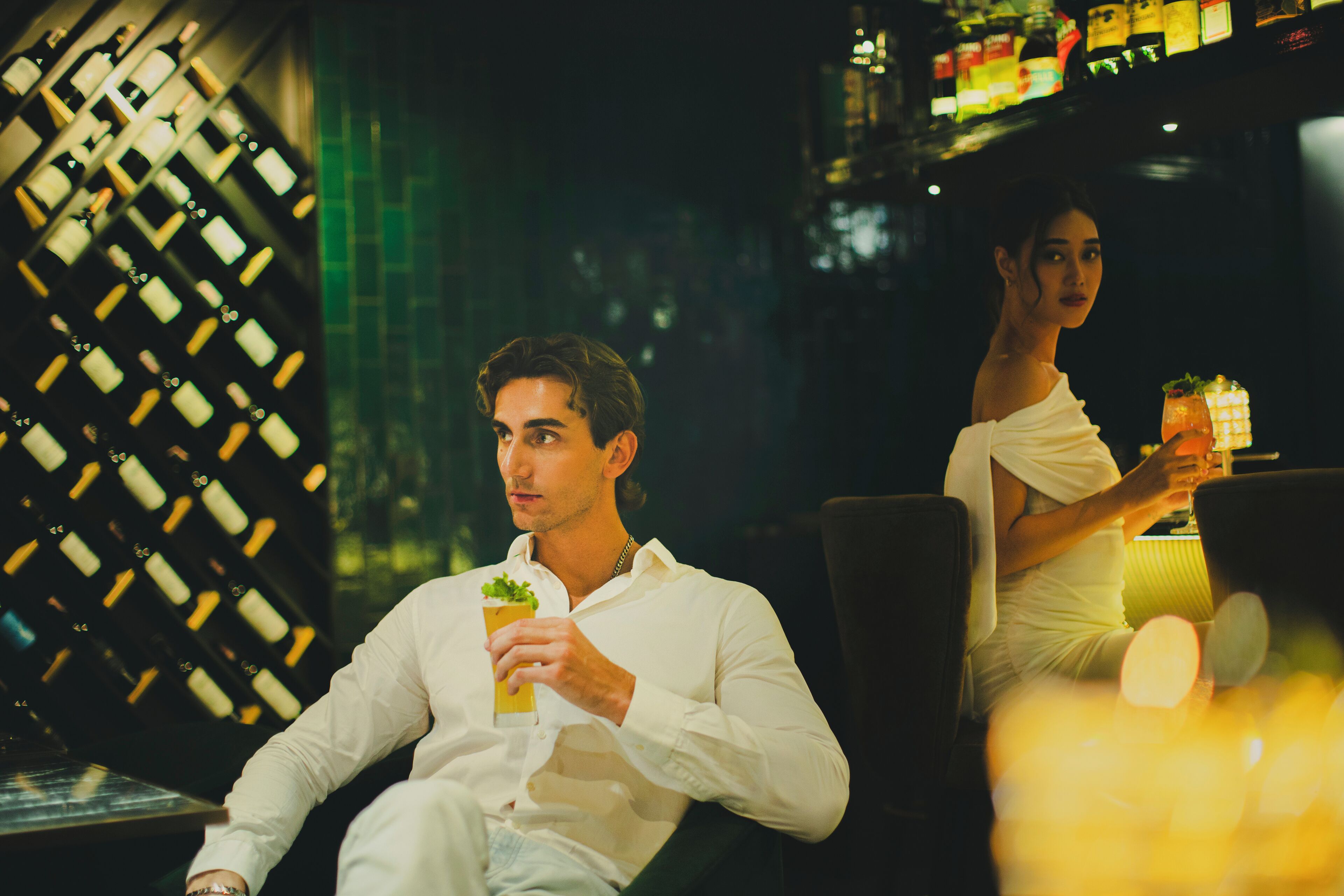 A bar area with a wine rack and a person holding a drink.