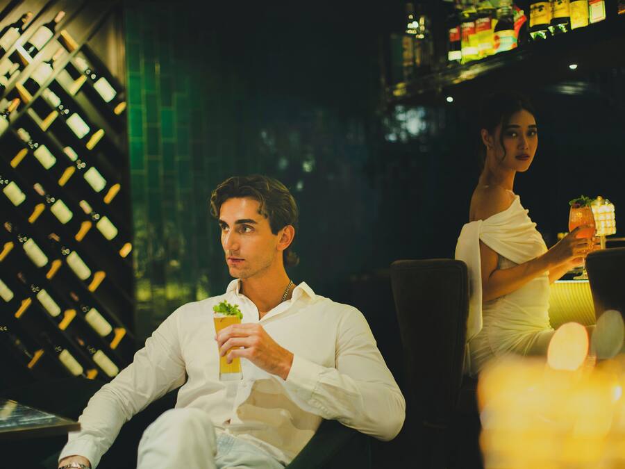 A bar area with a wine rack and a person holding a drink.