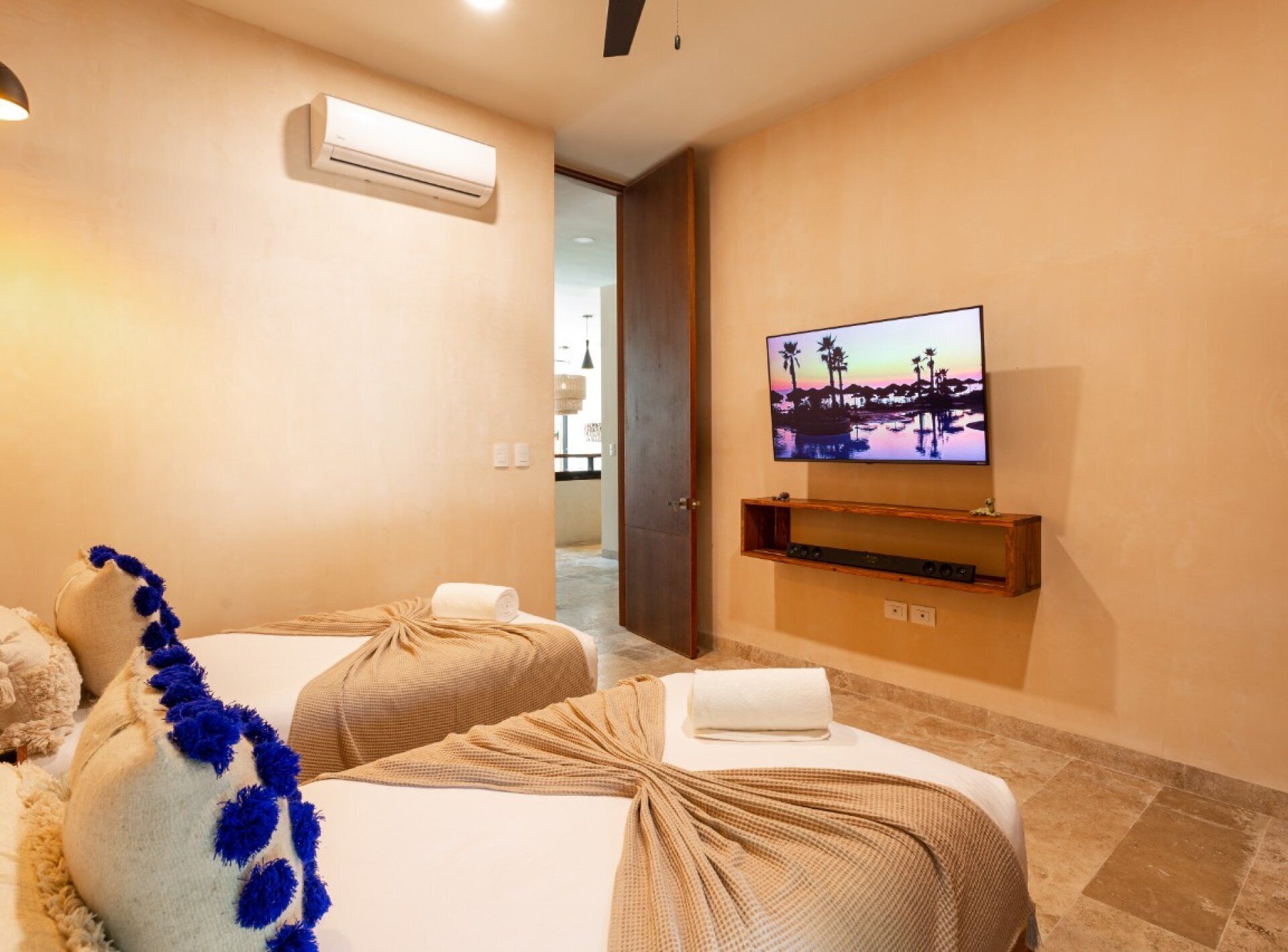 Une chambre d’hôtel avec deux lits, un téléviseur fixé au mur et un appareil de climatisation.