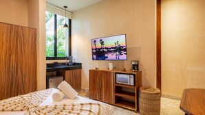 Una habitación de hotel con una cama, televisión, cafetera y una pequeña kitchenette.