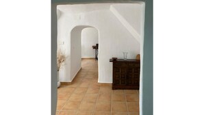 Un passadís interior amb sòl de rajola, un armari de fusta i una porta que condueix a una altra habitació.