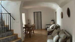 Un espai saló ampli amb un sofà, una taula de dinar i una escala.