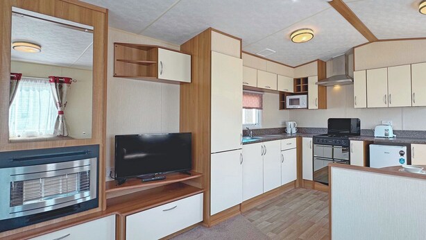 A compact kitchen with a TV, microwave, and stove.
