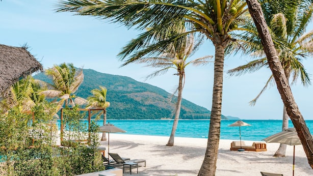 Ein Poolbereich mit Liegestuhl, einer Holzterrasse und Blick auf Strand und Meer.