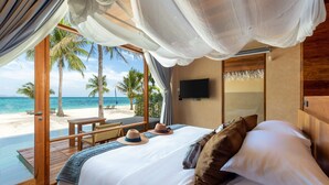 Ein Schlafzimmer mit einem großen Bett, einem Fernseher und Blick auf Strand und Meer.