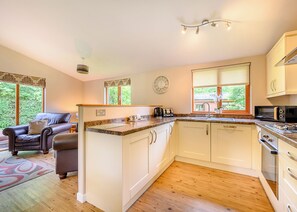 A kitchen with a central island, white cabinets, a microwave, and a clock on the wall.