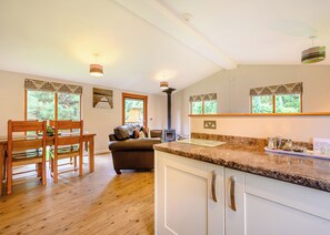 Une cuisine dotée d’un plan de travail en granit, de meubles en bois et d’un coin repas avec une table et des chaises.