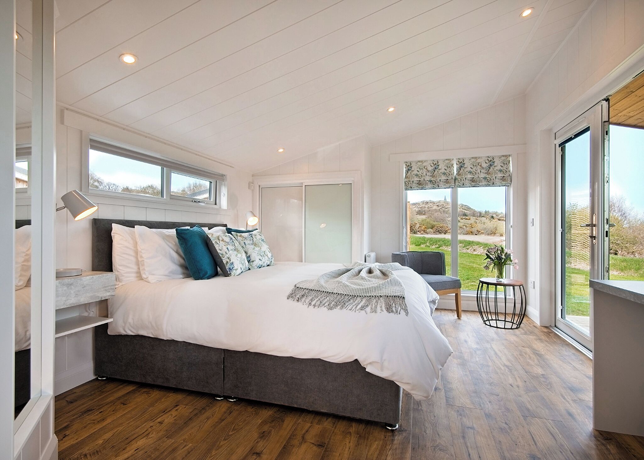 A bedroom with a large bed, a desk, and a view of the outdoors.
