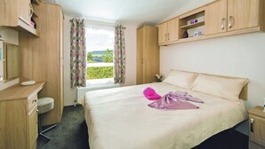 Une chambre d’hôtel équipée d’un lit, d’un bureau, d’une chaise, d’une fenêtre avec des rideaux et offrant une vue sur l’extérieur.
