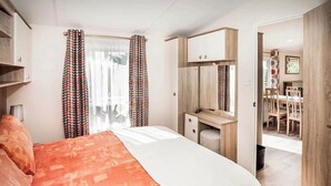 Une chambre à coucher comprenant un lit, un bureau, un miroir et donnant sur un coin repas.