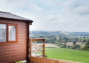 A wooden cabin with a balcony overlooking a green valley.