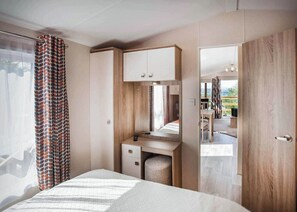 Een slaapkamer met een bed, een bureau, een spiegel en een kledingkast.